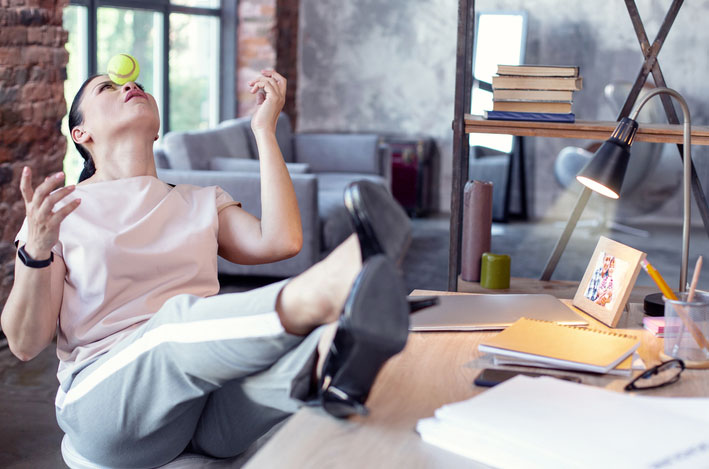 Worker procrastinating by trying to balance a ball on her nose
