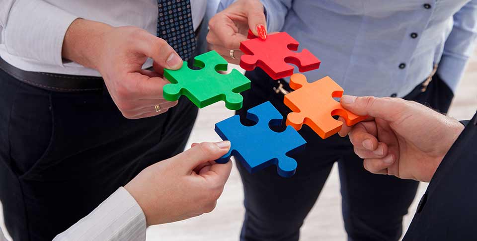 adults holding interlocking puzzle pieces, not yet assembled