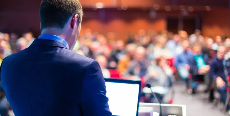 back of man presenting to a large audience