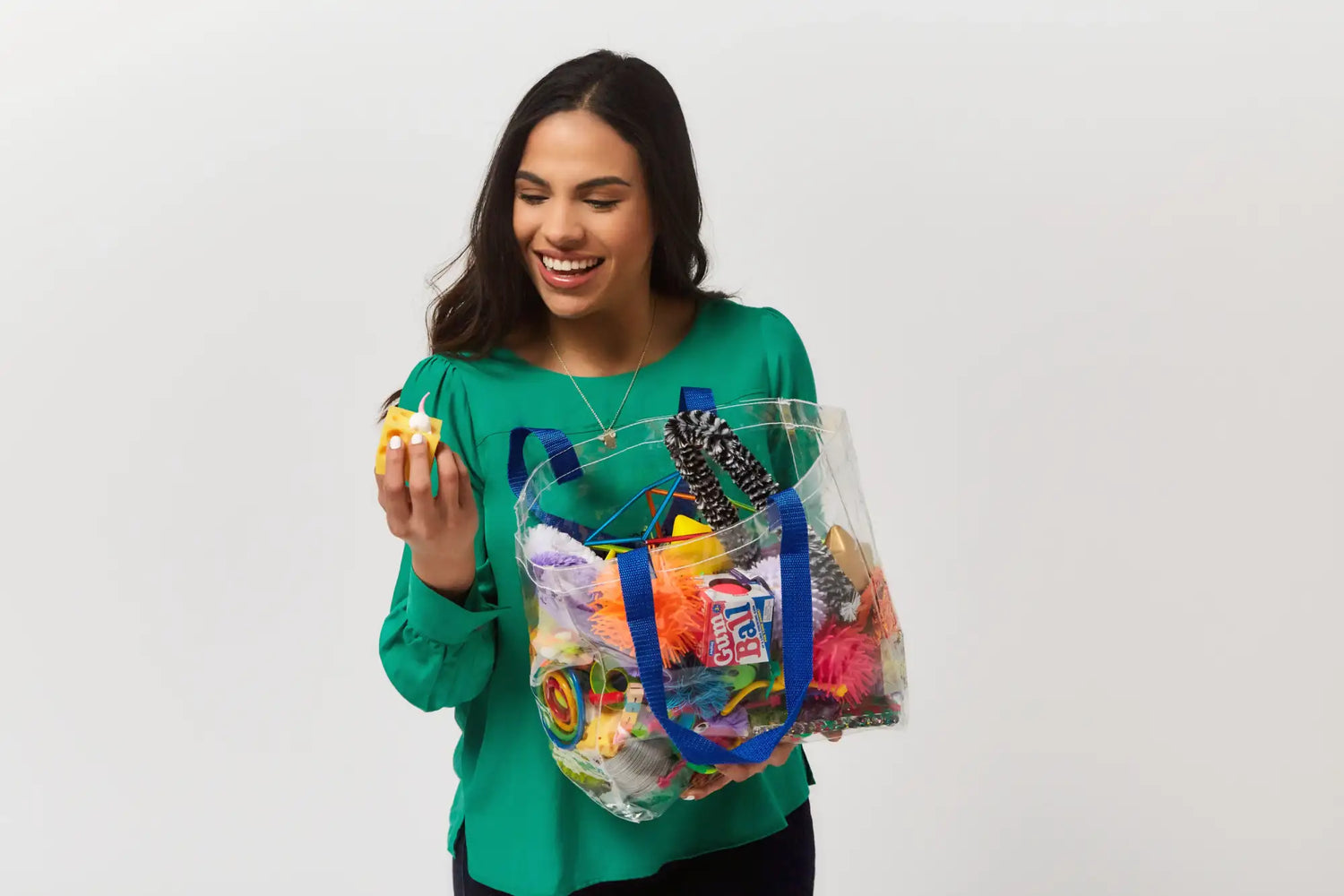 Transparent plastic tote bag with blue handles and colorful contents