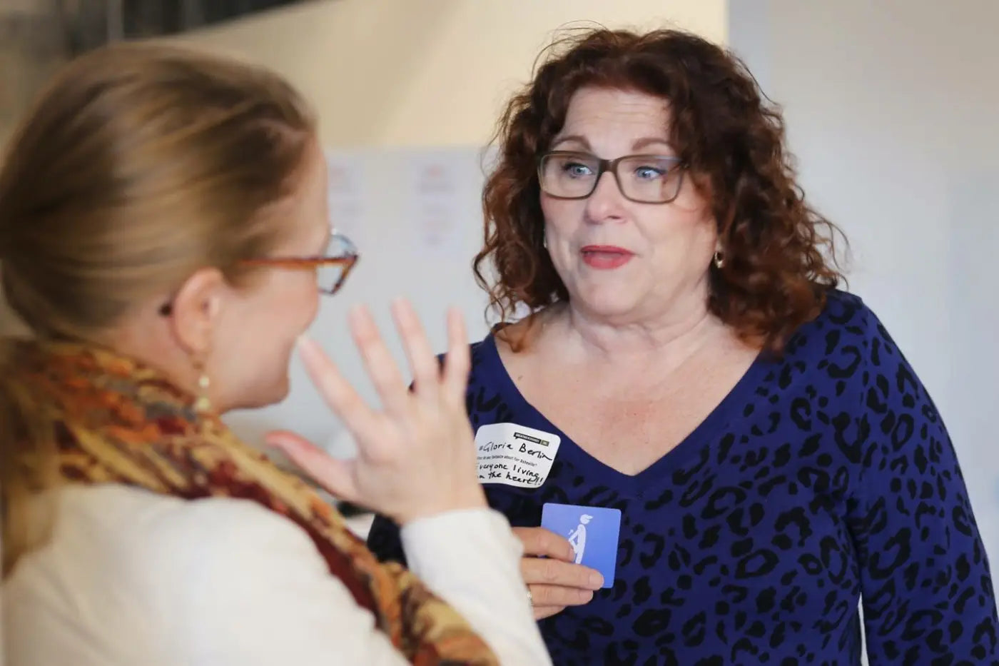 Two women engaged in a conversation around a blue WeConnect card