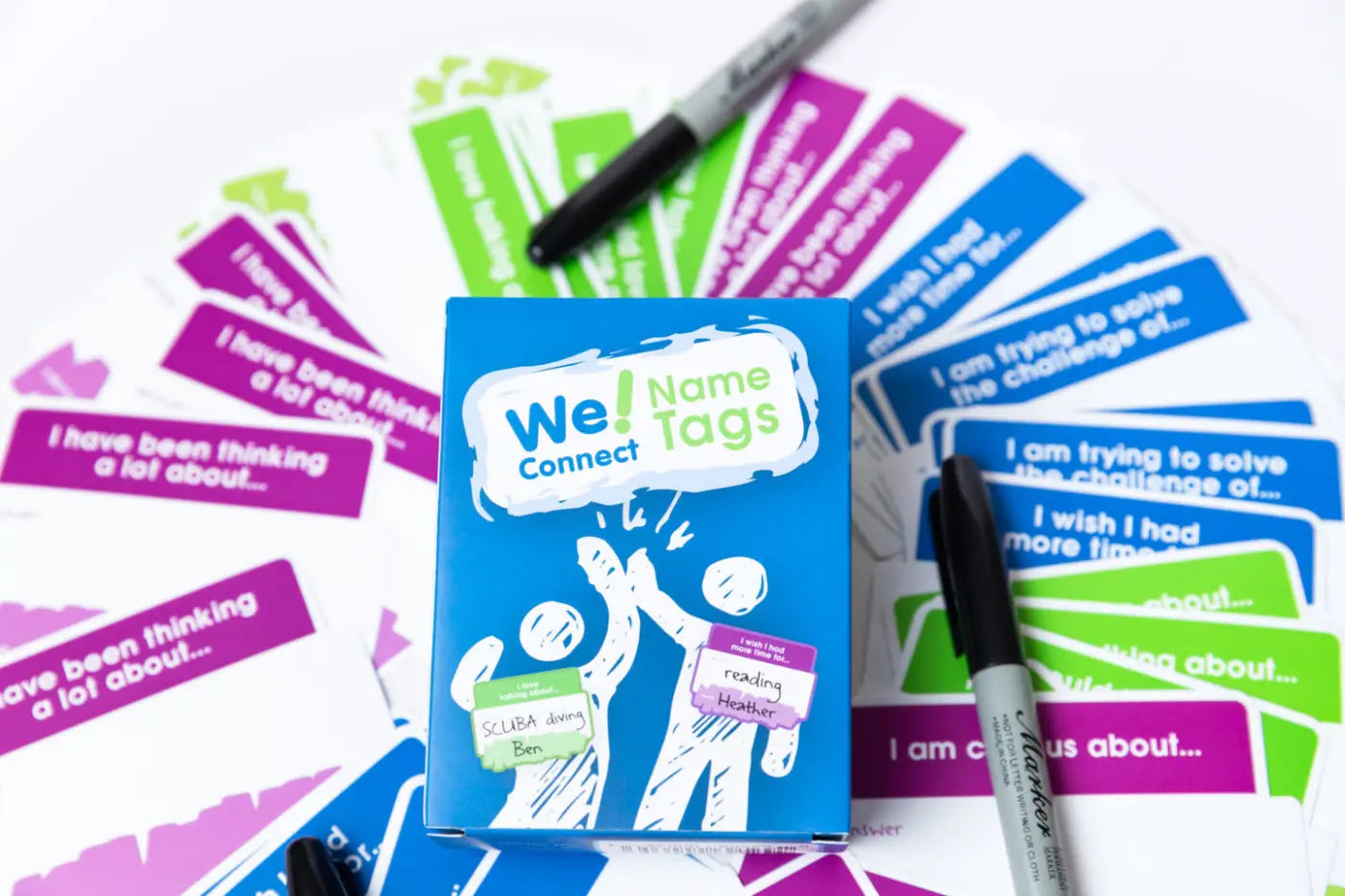 Box of 'We Name Tags' conversation starter name tags and markers on a white background